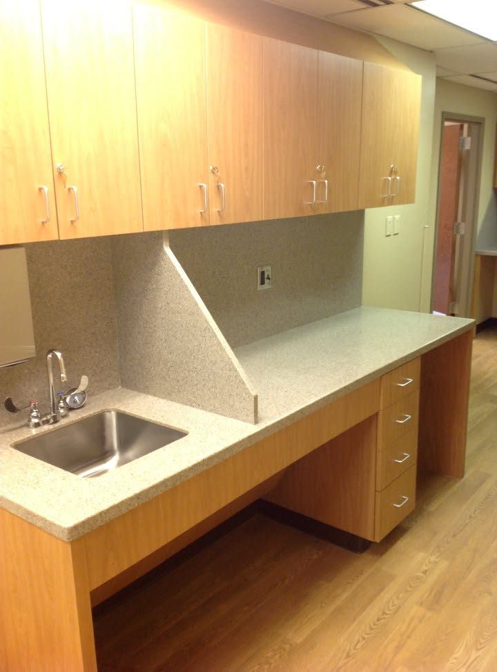 Clinic sink station with a solid surface countertop, backsplash and side splash, undermount sink, drawer stack and open knee space