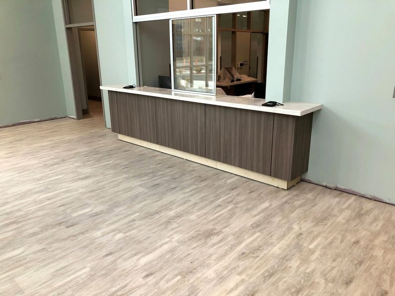 Woodgrain plastic laminate transaction counter with a solid surface transaction top below a teller window